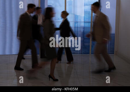 Blurred motion of business people walking in office corridor Stock Photo