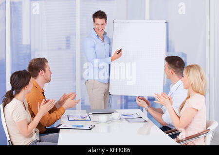 Young business people clapping for male colleague after presentation in office Stock Photo