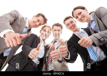 Low angle portrait of confident business team showing thumbs up against white background Stock Photo