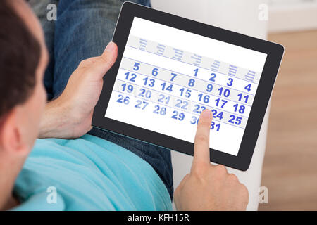 Closeup of man using calendar on digital tablet at home Stock Photo