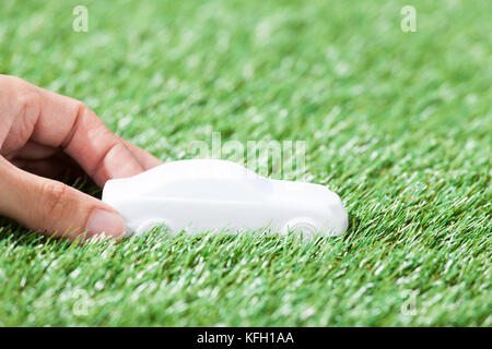 Closeup of hand holding car model in green field Stock Photo