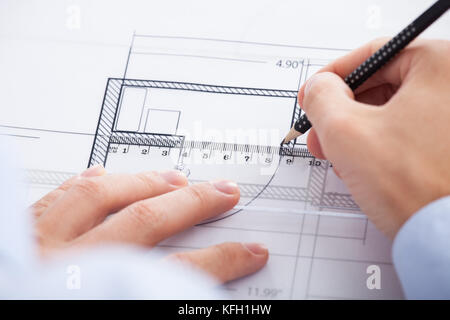 Closeup of architect's hands using pencil and ruler on blueprint in office Stock Photo