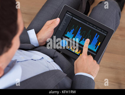 Overhead view of businessman analyzing graphs on digital tablet in office Stock Photo