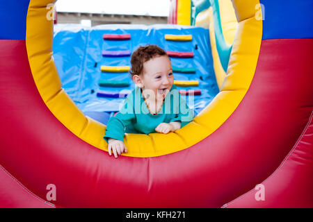 Happy laughing adorable toddler peeking out on trampoline Stock Photo