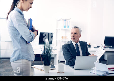 Dissatisfied box giving young female employee lecture Stock Photo