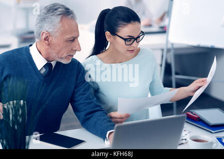 Coworkers in casual discussing printouts with diagrams Stock Photo