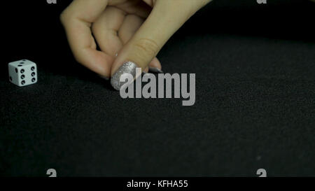 Detail of dice on black table. Female hand picks two dice from the table. Close up. Stock Photo