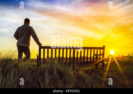 Southport, Merseyside, UK. 29th October 2017. UK Weather: A man watches a beautiful sunrise over the Marshside RSPB nature reserve at Southport in Merseyside.  This protected wetlands area is home to thousands of migratory birds over the winter season. Whooper Swans and Canadian pink footed Geese thrive in these affluent feeding grounds.  Credit: Cernan Elias/Alamy Live News Stock Photo