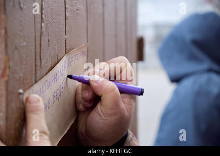 Kryvyi Rih, Ukraine. 29th October, 2017. Hand with felt pen writing Theses on th brown paper with blurred man in hood plaing Martin Luther during event dedicated to Reformation 500th Anniversary Credit: Dmytro Aliokhin/Alamy Live News Stock Photo