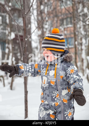 Happy child winter outdoors shows on something by hand and laughs Stock Photo