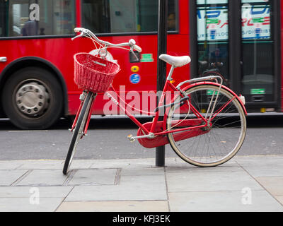 An elegant lady's red bicycle chained to a lampost in central London Stock Photo