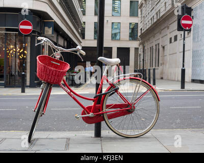 An elegant lady's red bicycle chained to a lampost in central London Stock Photo