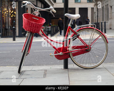 An elegant lady's red bicycle chained to a lampost in central London Stock Photo