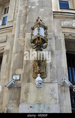 Budapest, Dorottya utca 5, Post Office, anno MCMXII (1912) - ornate lamp offset by modern CCTV cameras mounted on the facade of the building Stock Photo