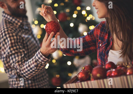 Red bauble ornament for Christmas tree in man's and woman's hands, close up Stock Photo