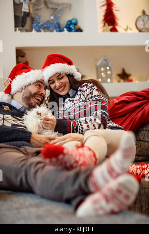 Cheerful pair in Christmas night enjoying in bad with their dog Stock Photo