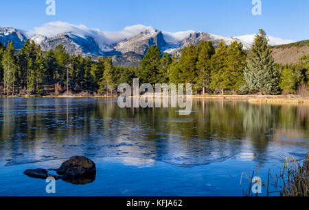 Ice Forms on Sprague Lake as winter approaches in Rocky Mountain National Park Stock Photo