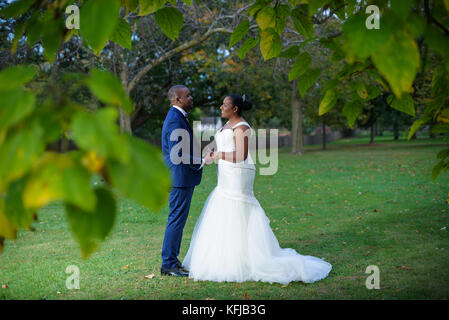 Newlyweds holding hands and facing each other in a garden scene Stock Photo