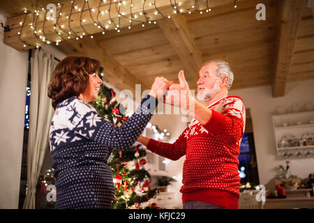 Senior couple dancing by Christmas tree in the evening. Stock Photo