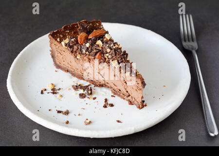 Chocolate cheesecake slice with crushed nuts on white plate. Slice of chocolate cake Stock Photo