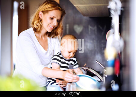 Young mother with a baby boy doing housework. Stock Photo