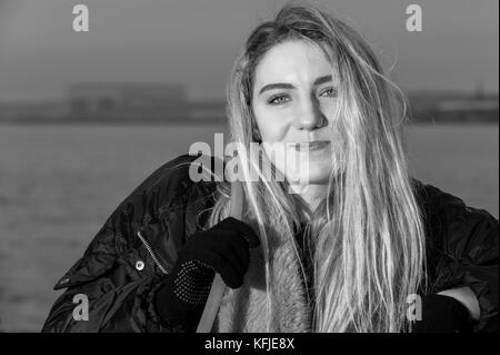 Portrait of girl looking at camera, leaning against promenade railings, black and white. Stock Photo