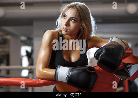 Young pretty boxer woman standing on ring. Full body portrait of