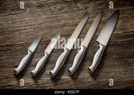 Metal kitchen knives set on rustic wood background Stock Photo