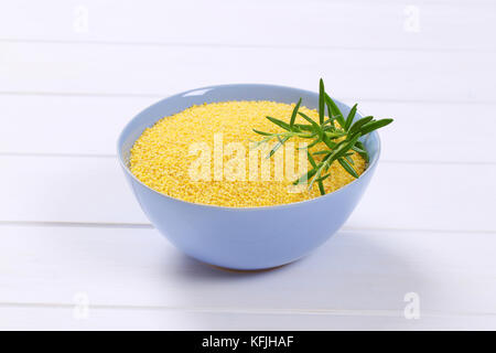 bowl of raw millet on white wooden background Stock Photo