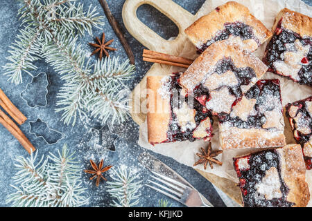 Sweet Christmas berry pie in Christmas decorations, dark background. Christmas food concept. Stock Photo