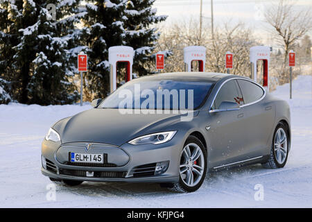 PAIMIO, FINLAND - JANUARY 17, 2016: Unidentified man drives Tesla Model S at Supercharger Station Paimio on a cold wintery day. Unlike conventional ca Stock Photo