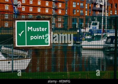Green muster point sign at Ipswich marina on a bright autumn afternoon. Stock Photo