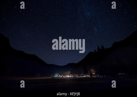Night landscape, illuminated alpine lodge, mountain silhouette and starry sky Stock Photo