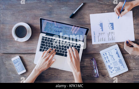 Meeting of financial people discussing report and business analytics charts and graphs on digital tablet computer, laptop and smartphone screen on a w Stock Photo