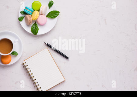 Cup of coffee with colorful macaron or macaroon with blank paper. Flat lay Stock Photo