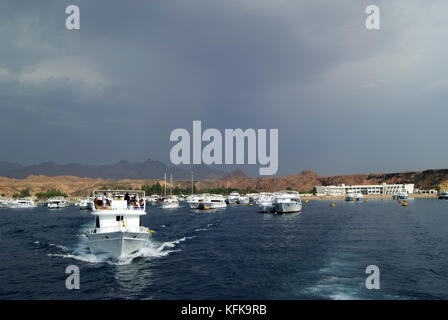 EGYPT, SHARM EL SHEIKH - SEPTEMBER 21, 2010: tourist yachts for walks and diving go to sea from the bay in sunny weather; view from the side of one of Stock Photo