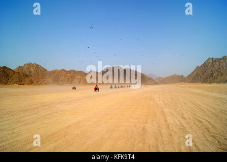 EGYPT, SHARM EL SHEIKH - SEPTEMBER 23: a tourist group travels through the Egyptian desert on ATVs; the chain of quads leaves the viewer towards the m Stock Photo