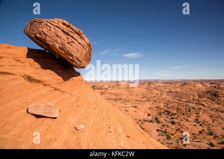 A large sandstone boulder rests precariously over a slope in the desert of the Escalante - Grand Staircase National Monument. The boulder appears to b Stock Photo