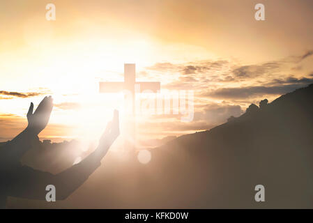 Human hands raising hand while praying to jesus on sunset background Stock Photo