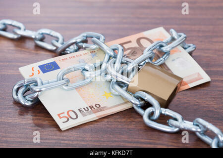 Fifty euro notes with chain and padlock on table Stock Photo