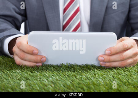 Midsection of businessman using digital tablet on grass Stock Photo