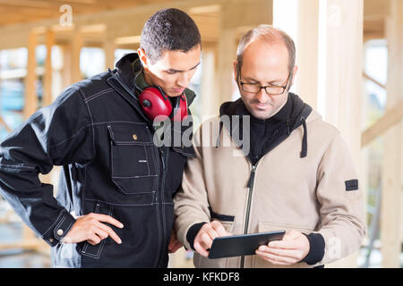 Carpenters Using Tablet Pc At Site Stock Photo