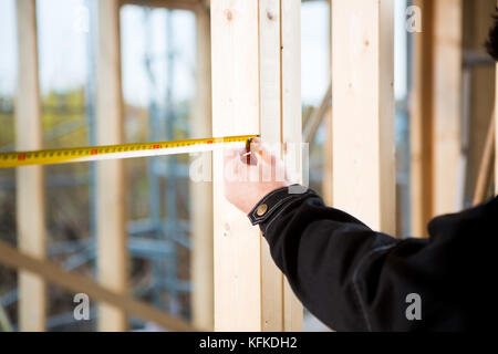 Cropped Image Of Carpenter Measuring Wood At Site Stock Photo