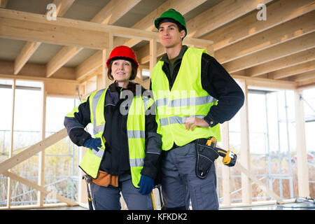 Confident Carpenters In Reflective Jackets At Construction Site Stock Photo
