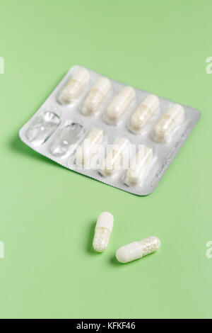 White capsules from foil blister pack on green background Stock Photo