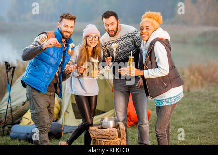 Friends in sweaters eating fondue outdoors Stock Photo