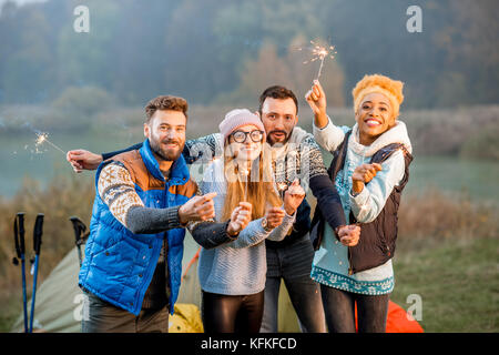 Friends in sweaters celebrating at the camping Stock Photo