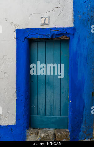 Door painted in blue, with a number 1 inscribed on a tile. Rectangular shapes. Stock Photo