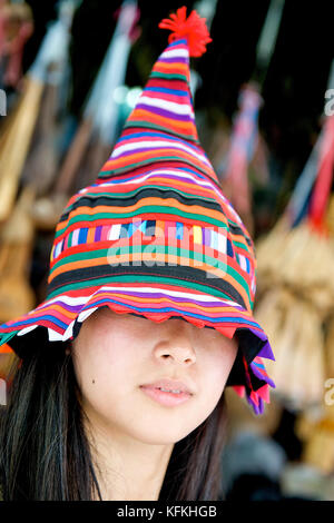 A young Asian girl shows her traditional Thai hat off at the famous Bangkok weekend market called Chatuchak market. Stock Photo