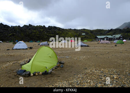 Campers in field and tents held down by rocks to avoid strong winds at Landmannalaugar campsite, Iceland Stock Photo